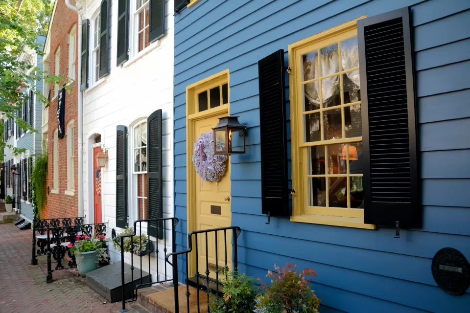 Line of blue, white, and red brick row homes with colorful doors and iron railings.